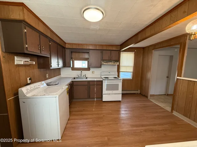 a kitchen with a sink a stove top oven and cabinetry