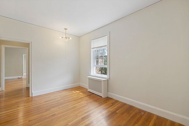 an empty room with wooden floor cabinet and windows