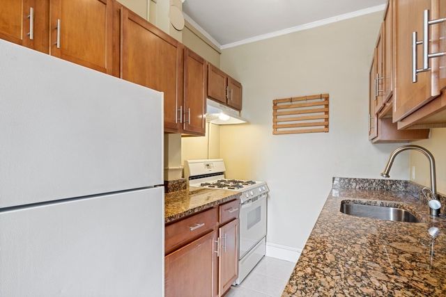 a kitchen with stainless steel appliances granite countertop a refrigerator a stove and a sink with wooden cabinets