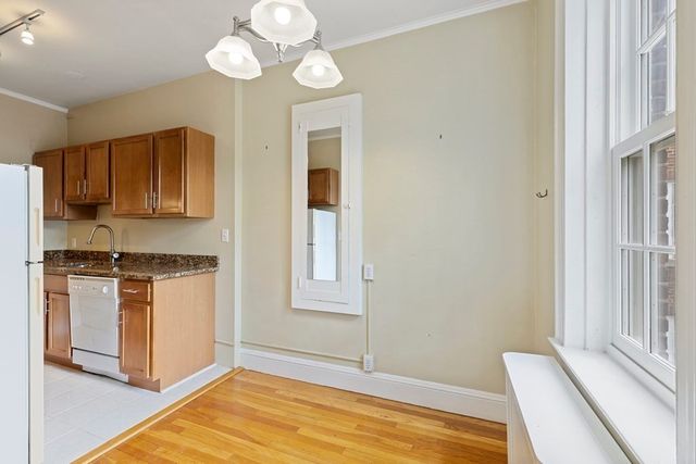 a kitchen with stainless steel appliances granite countertop a stove a sink and a refrigerator with wooden floors