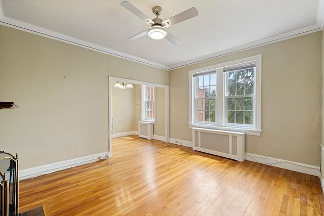 a view of an empty room with window and wooden floor