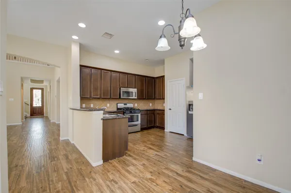 a kitchen with stainless steel appliances granite countertop a refrigerator a stove top oven a sink dishwasher and wooden floor