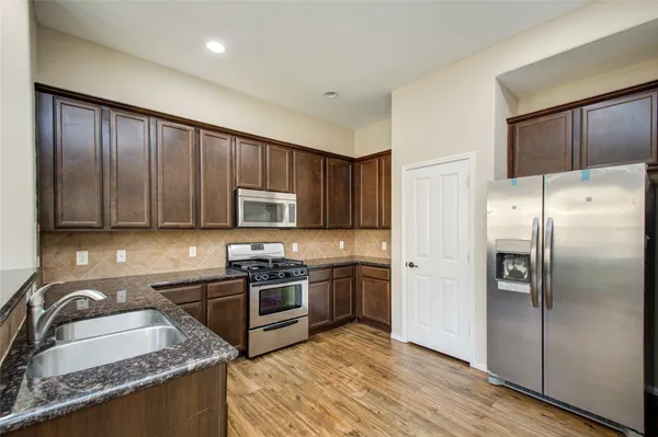a kitchen with stainless steel appliances granite countertop a refrigerator stove and sink