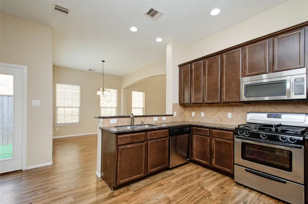 a kitchen with stainless steel appliances granite countertop wooden cabinets stove top oven and sink