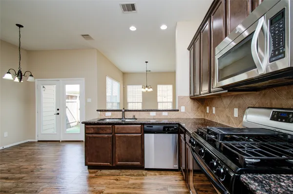 a kitchen with stainless steel appliances granite countertop a stove a sink and a microwave