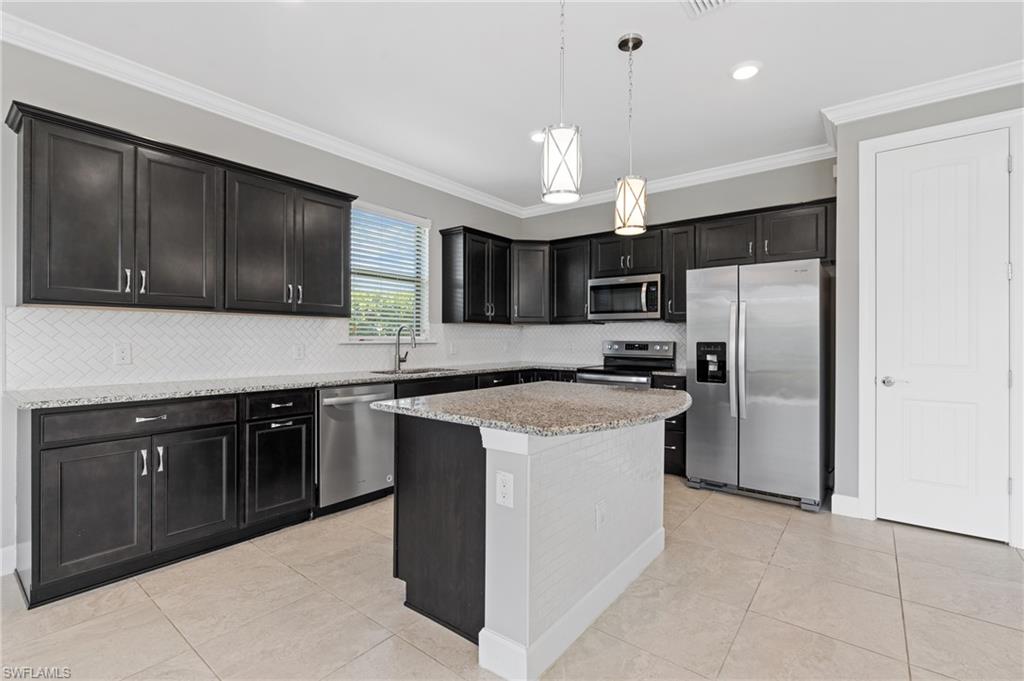 19953 Beverly Park Road Estero, FL 33928 - Photo 9 of 50 Kitchen featuring light tile patterned flooring, a sink, stainless steel appliances, pendant lighting, and crown molding