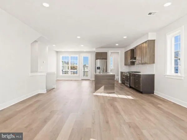 a view of an empty room with kitchen and window