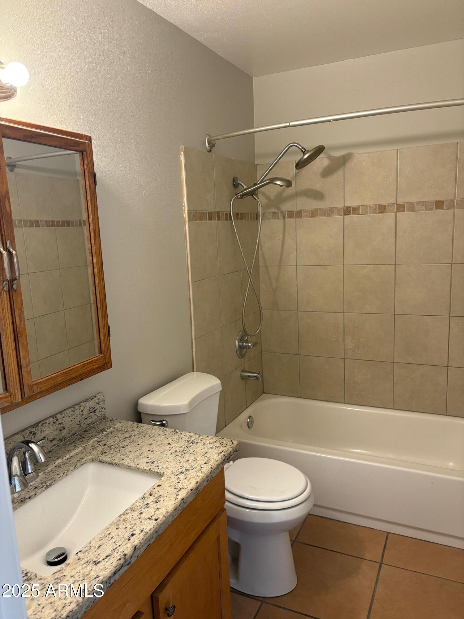 909 South Priest Drive, Unit 10 Tempe, AZ 85281 - Photo 4 of 14 a bathroom with a granite countertop bathtub sink vanity mirror and toilet