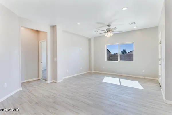 an empty room with wooden floor and ceiling fan