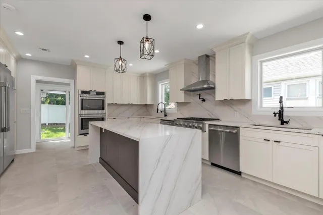 a kitchen with stainless steel appliances granite countertop a sink a stove and a refrigerator