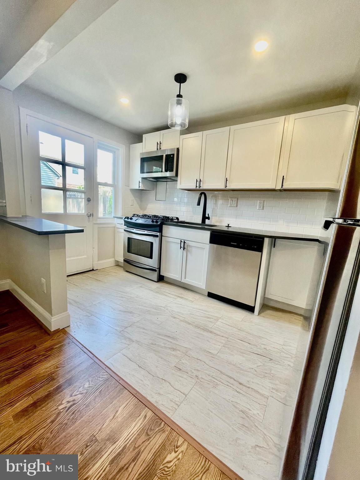 2809 A 16th Road South, Unit 2809A Arlington, VA 22204 - Photo 10 of 13 a large kitchen with stainless steel appliances granite countertop a stove a sink dishwasher and a microwave with wooden floor