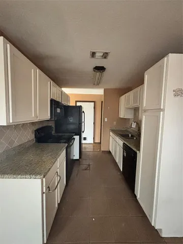 a kitchen with granite countertop a refrigerator a stove a sink a counter top space and cabinets