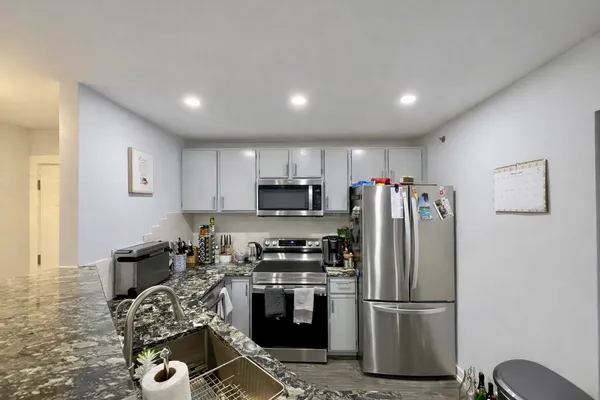 a kitchen with stainless steel appliances granite countertop a refrigerator sink and stove