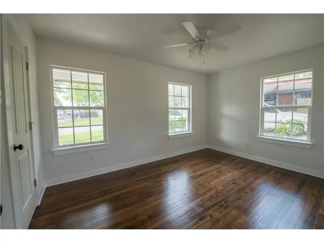 a view of an empty room with a window and wooden floor