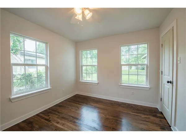 an empty room with wooden floor and windows