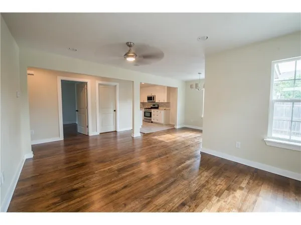 a view of an empty room with window and wooden floor