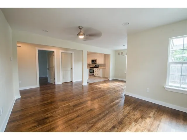 a view of an empty room with window and wooden floor