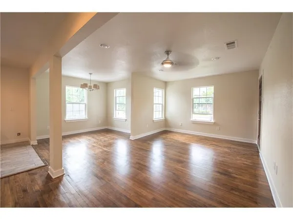 a view of an empty room with a window and wooden floor