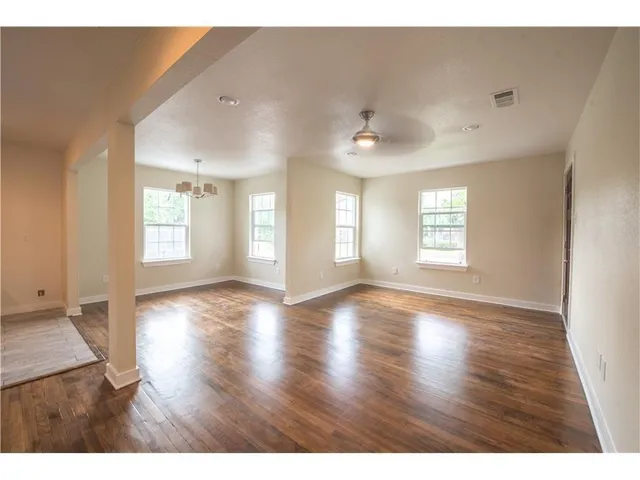 a view of an empty room with a window and wooden floor