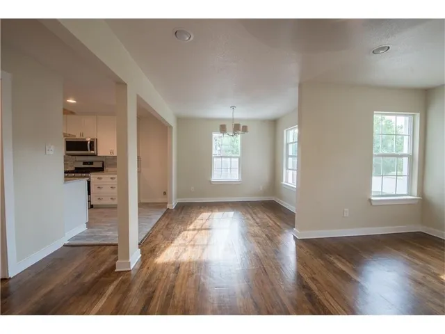a view of an empty room with window and wooden floor