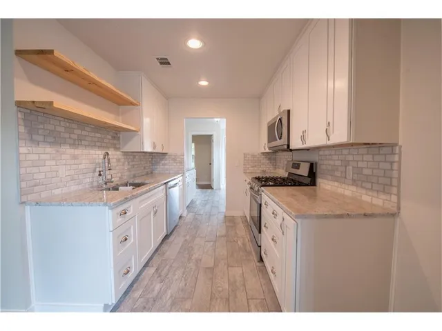 a kitchen with granite countertop a sink stove top oven and cabinets