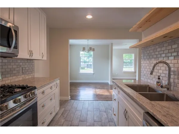 a kitchen with granite countertop a sink stainless steel appliances and cabinets