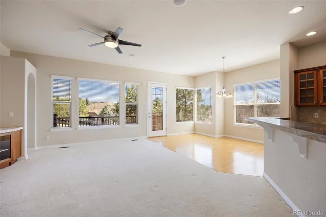 a view of an empty room with a window and a kitchen