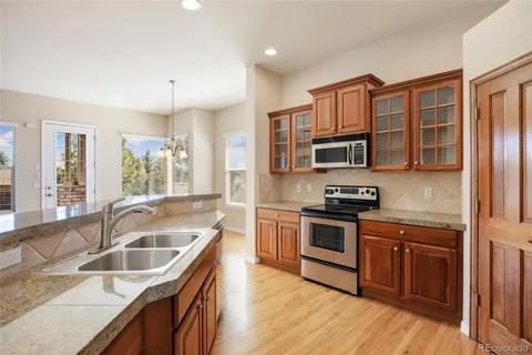 a kitchen with granite countertop a sink wooden cabinets and stainless steel appliances