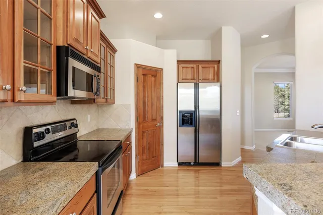 a kitchen with stainless steel appliances granite countertop a refrigerator a stove and a sink with wooden floor