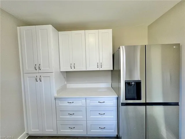 a kitchen with white cabinets and refrigerator
