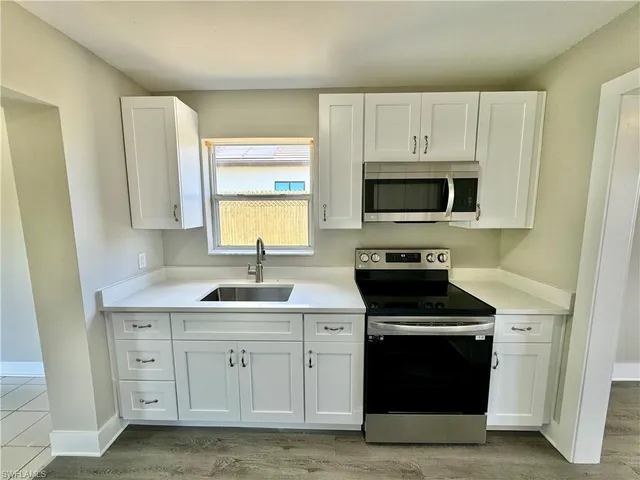 a kitchen with white cabinets stainless steel appliances and sink