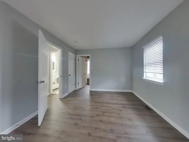 a view of an empty room with wooden floor and window