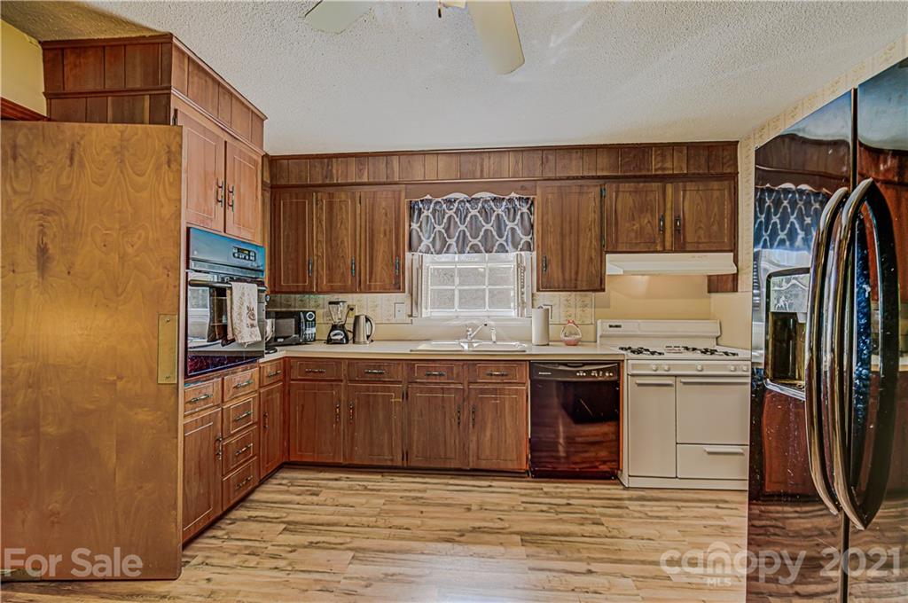 11328 Torino Road Matthews, NC 28105 - Photo 7 of 23 a kitchen with stainless steel appliances granite countertop a refrigerator a sink dishwasher a stove with wooden cabinets and floor