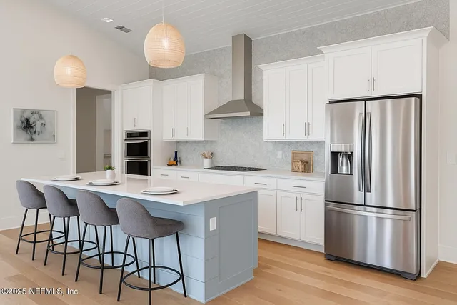 a kitchen with stainless steel appliances a refrigerator a stove a sink and white cabinets with wooden floor