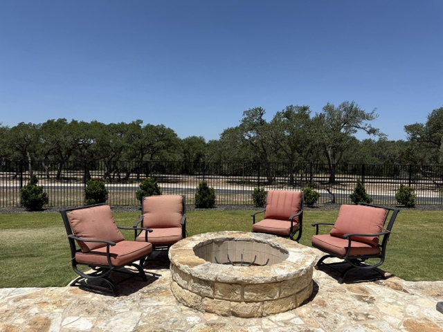 170 Climbing Rock Loop Dripping Springs, TX 78620 - Photo 28 of 30 An inviting stone fire pit and comfortable seating create a perfect gathering spot on the paved patio.