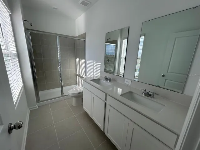 a bathroom with a double vanity sink toilet and shower