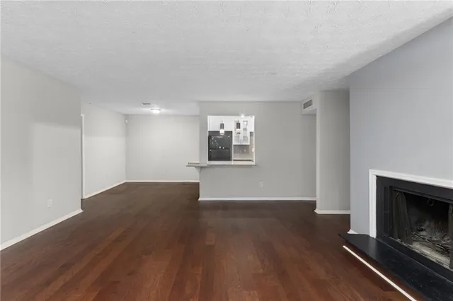 an empty room with wooden floor fire place and windows