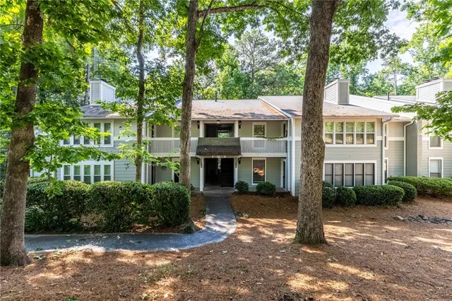 a front view of a house with garden and trees