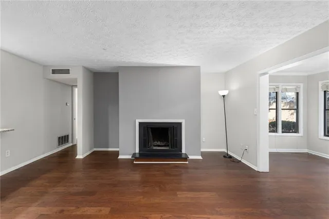 an empty room with wooden floor fireplace and windows