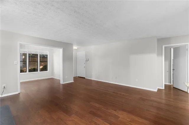 a view of an empty room with wooden floor and windows