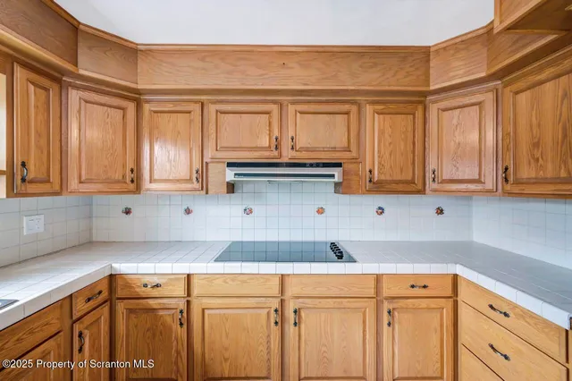 a kitchen with stainless steel appliances granite countertop a refrigerator a sink dishwasher a stove and white countertops with wooden floor