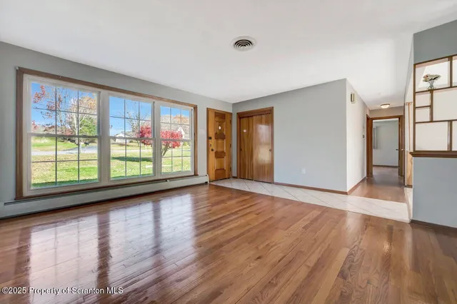 an empty room with wooden floor and windows