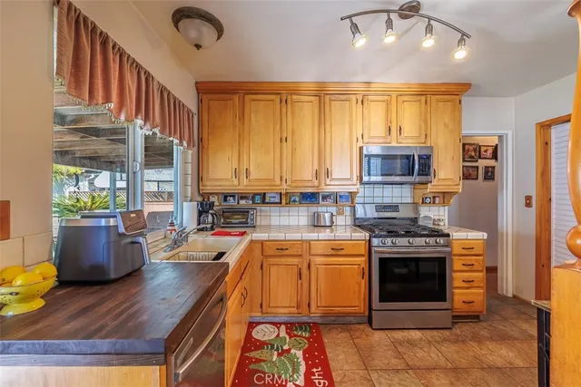 a large kitchen with stainless steel appliances granite countertop a stove top oven a sink dishwasher a dining table and chairs with wooden floor