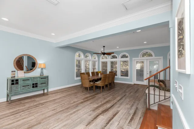 a dining room with wooden floor and large windows