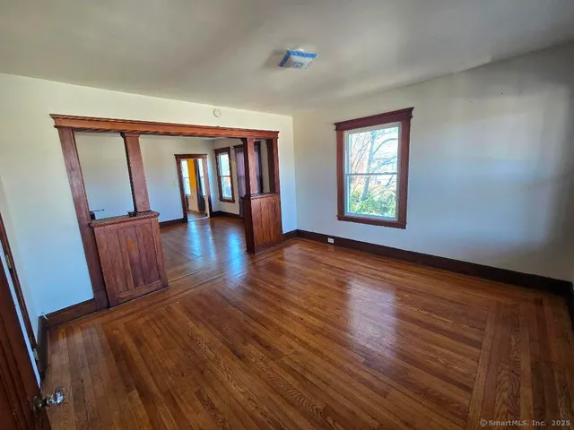 a view of an empty room with wooden floor and a window