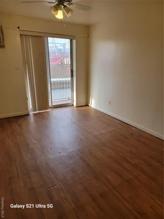 an empty room with wooden floor and windows with curtains