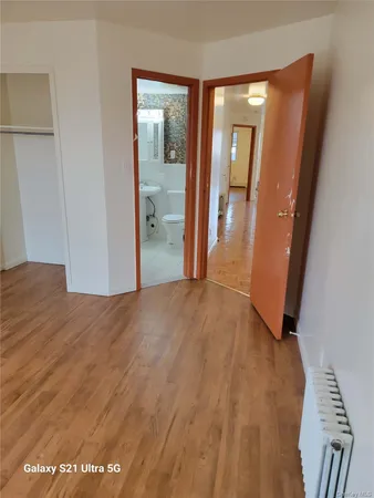 a view of a hallway with wooden floor and a bathroom