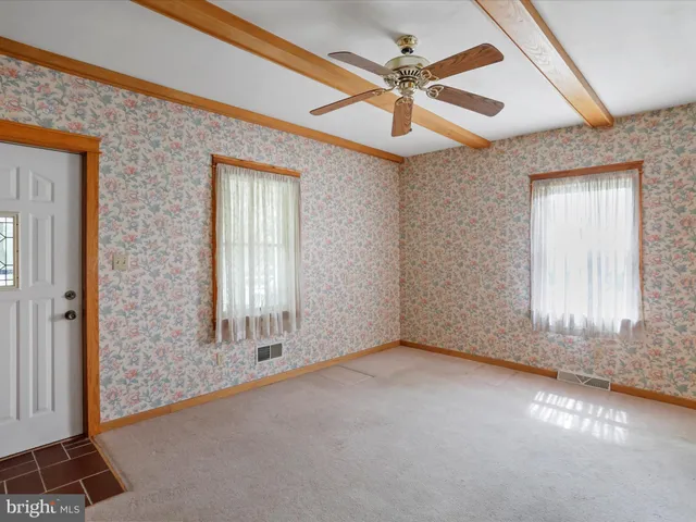an empty room with chandelier fan and windows