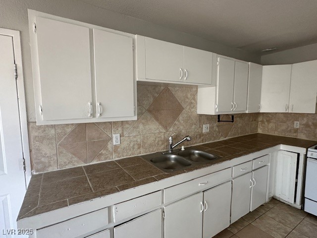 3106 Cummings Street North Las Vegas, NV 89030 - Photo 4 of 12 Kitchen with tile countertops, white cabinets, backsplash, light tile patterned floors, and white range oven