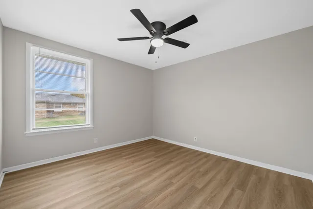 an empty room with wooden floor and ceiling fan